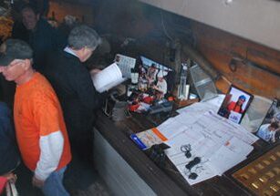 Men looking at documents on cluttered bar counter.